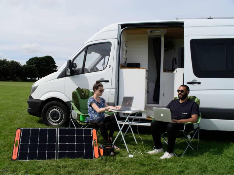 working on laptops in front of van