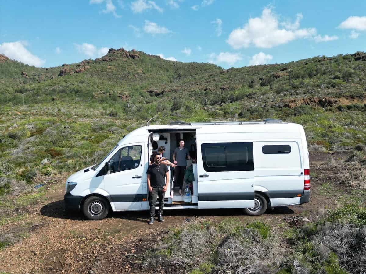 Family outside campervan against green hillside