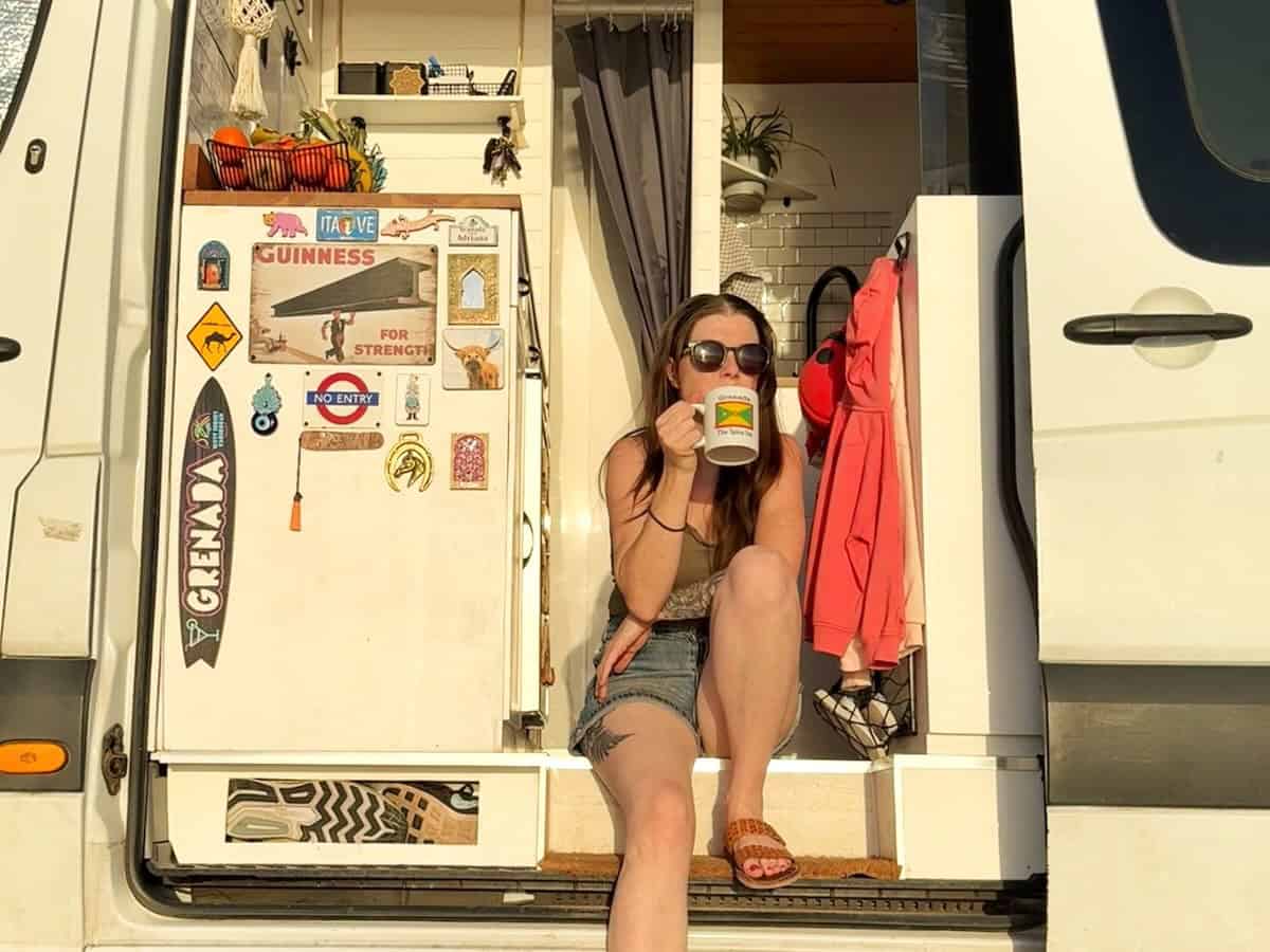 Woman driving coffee sat on campervan step