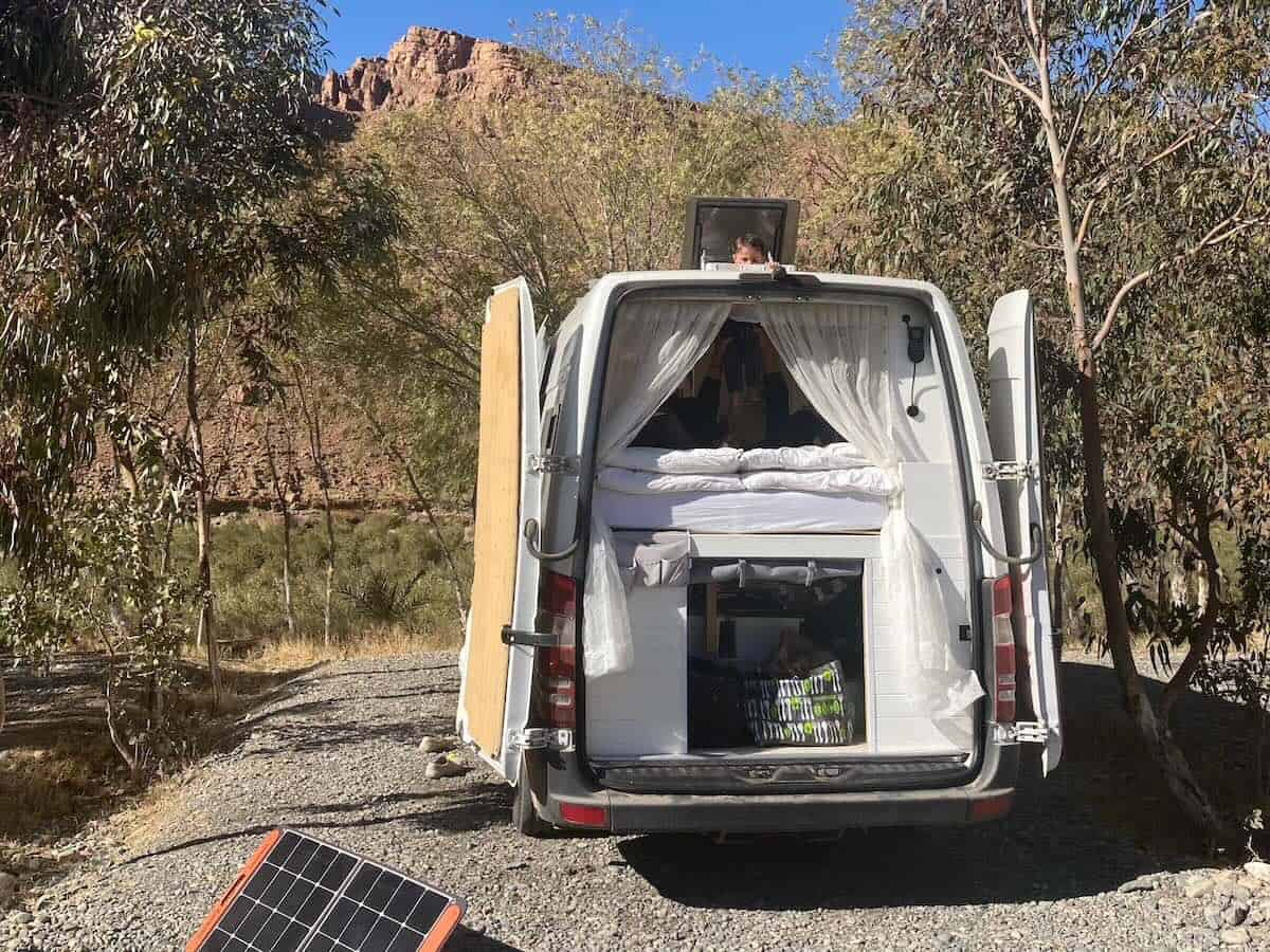 Campervan with back doors open against mountain backdrop